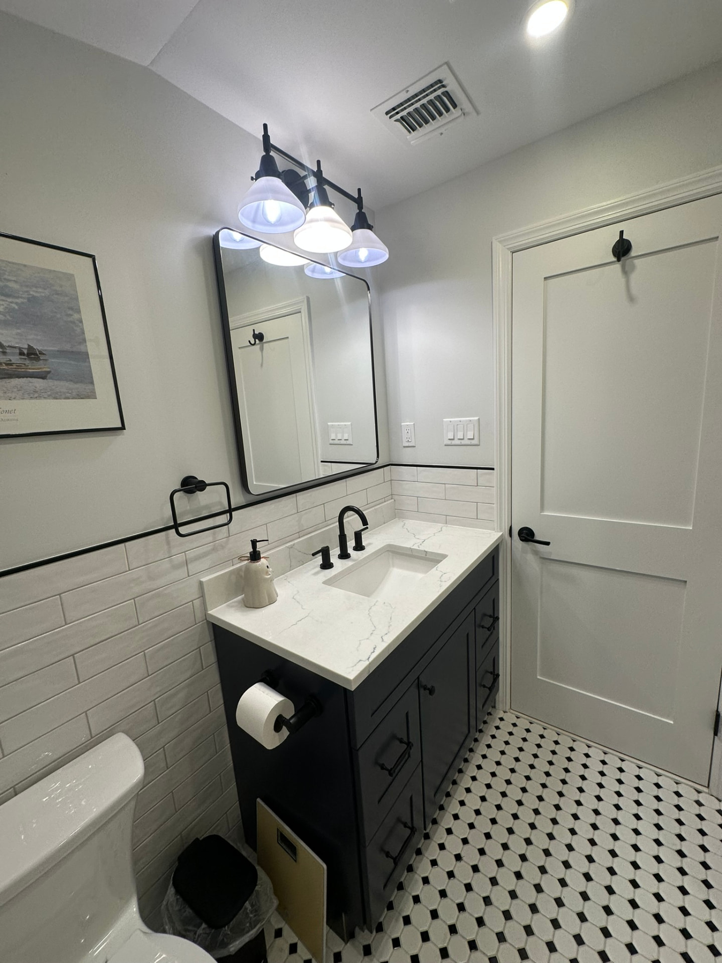 Bathroom remodel with navy vanity and black-and-white mosaic floor