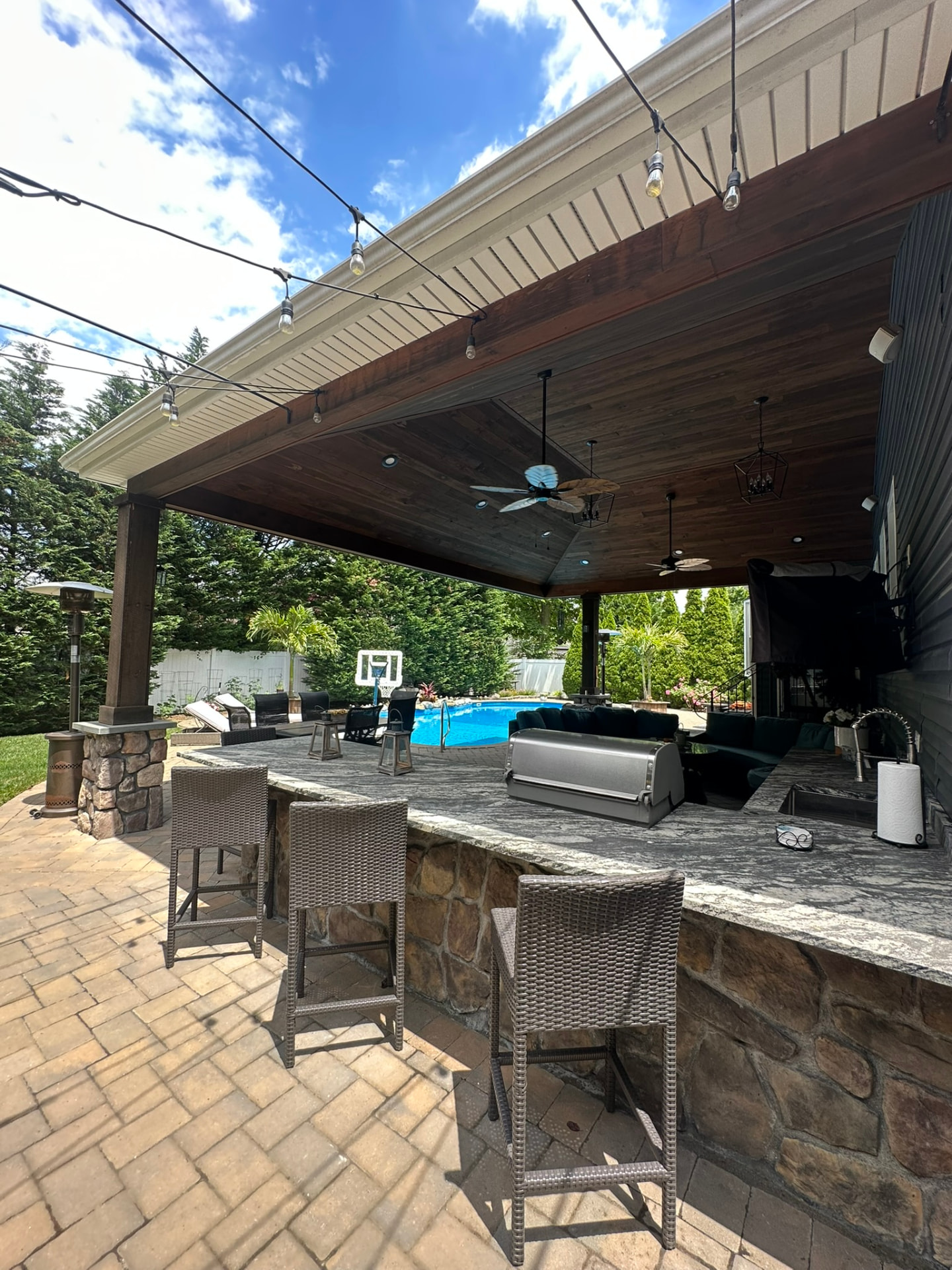 Covered outdoor kitchen and bar overlooking a pool