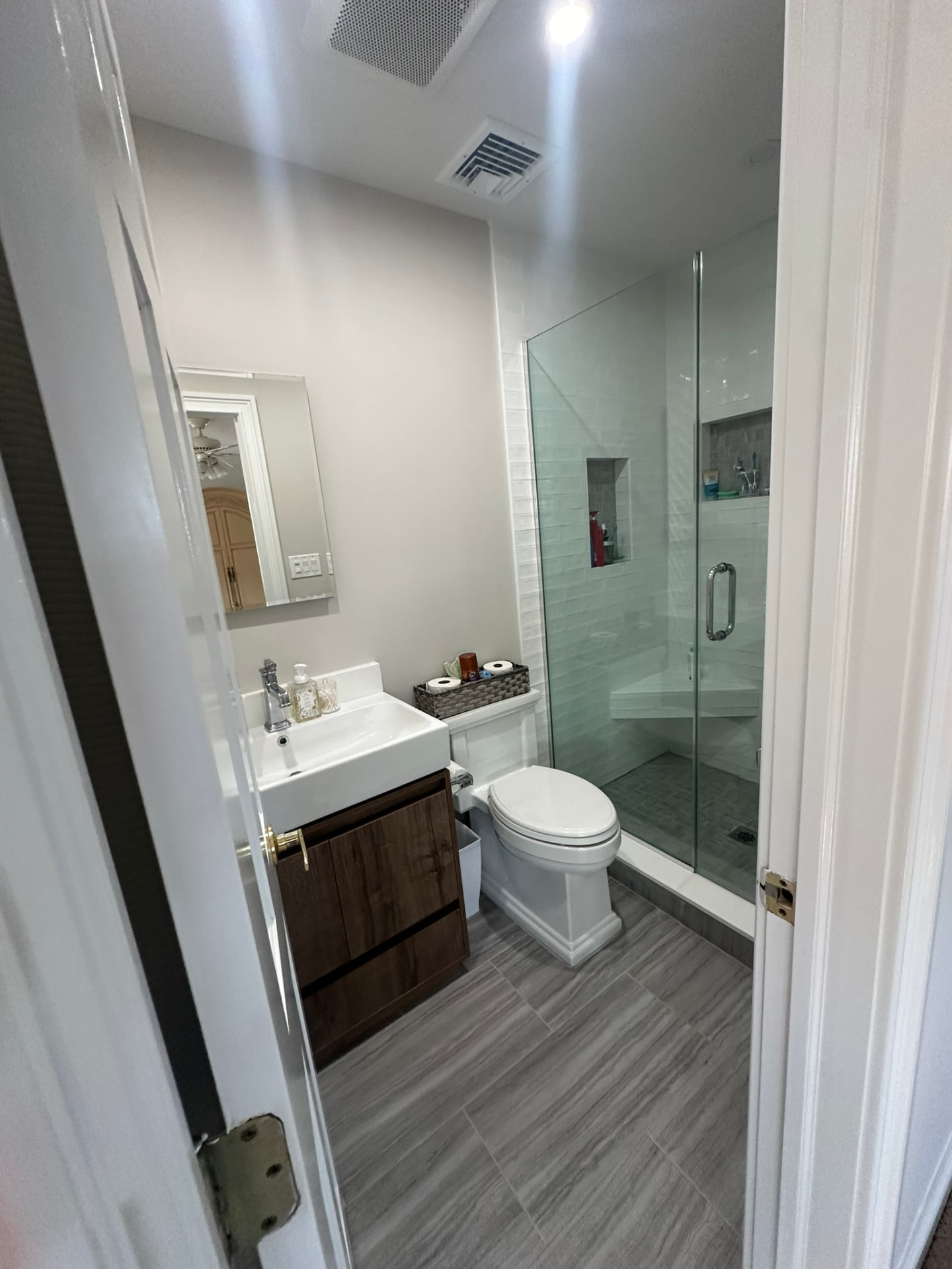Remodeled bathroom with walk-in glass shower and wood vanity