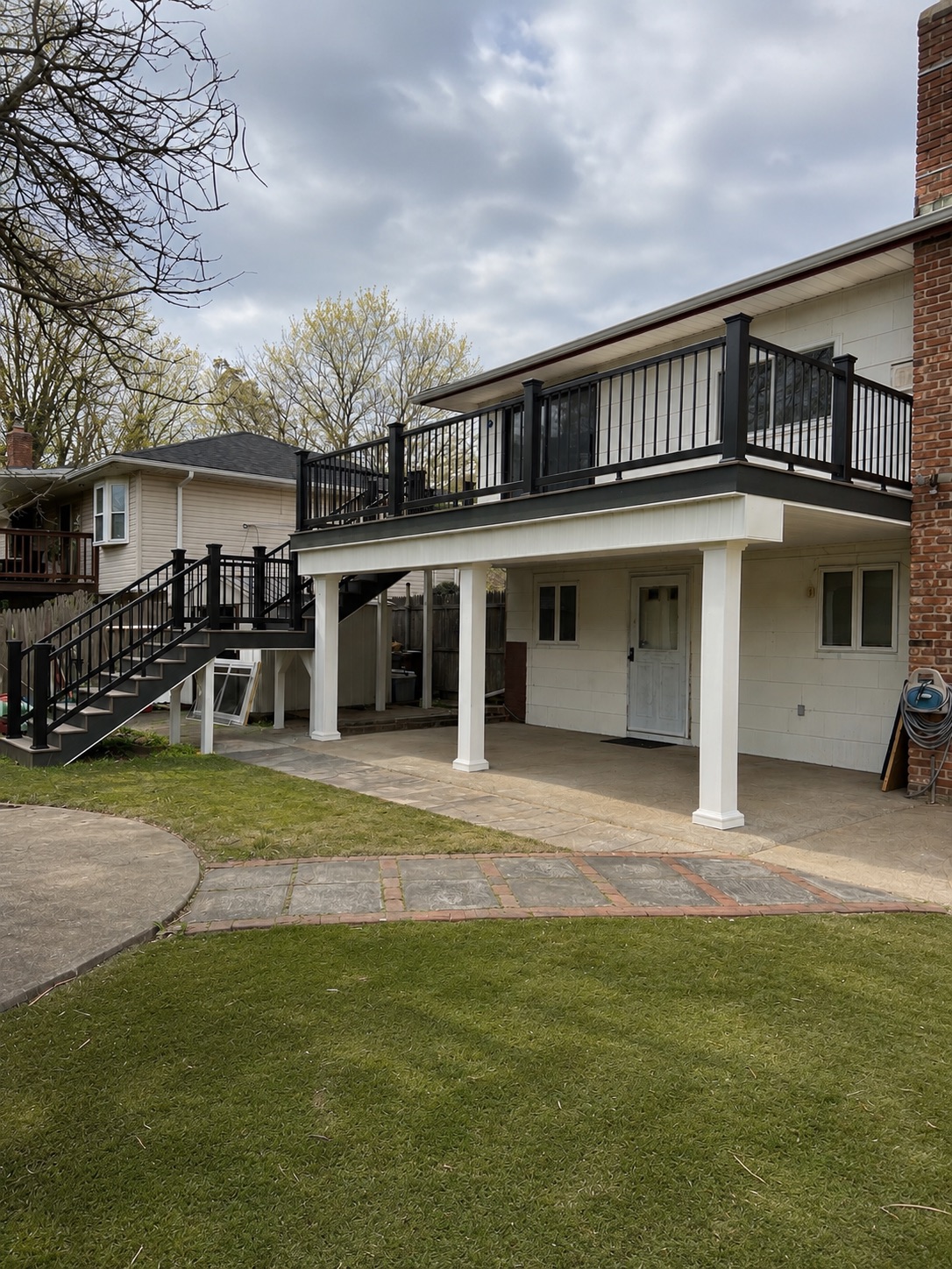 Elevated deck with black railings over a paver patio