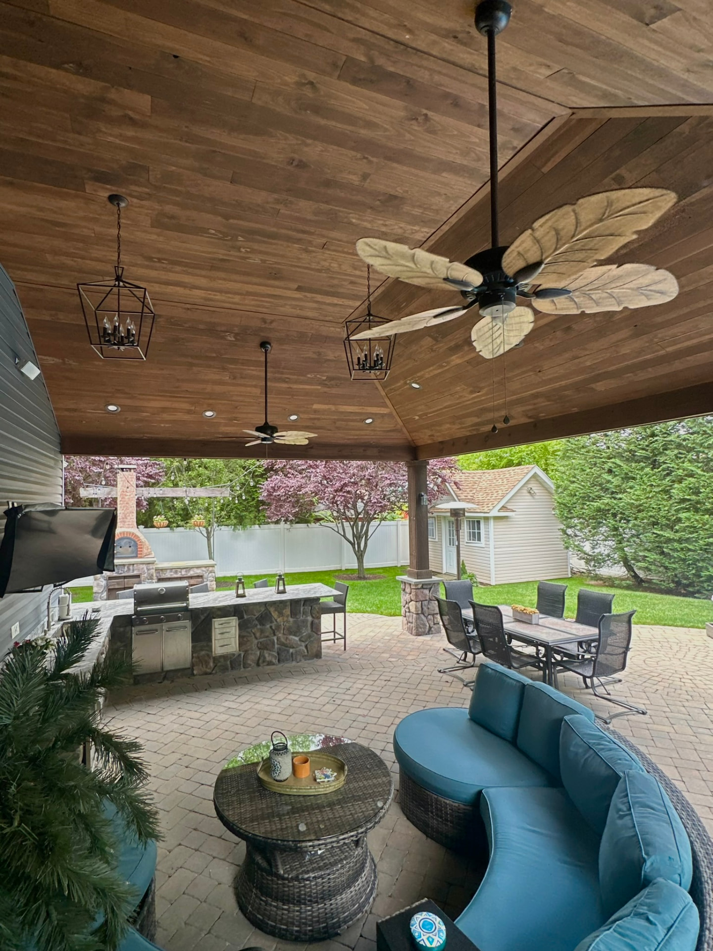 Covered patio with wood ceiling, fans, and outdoor kitchen