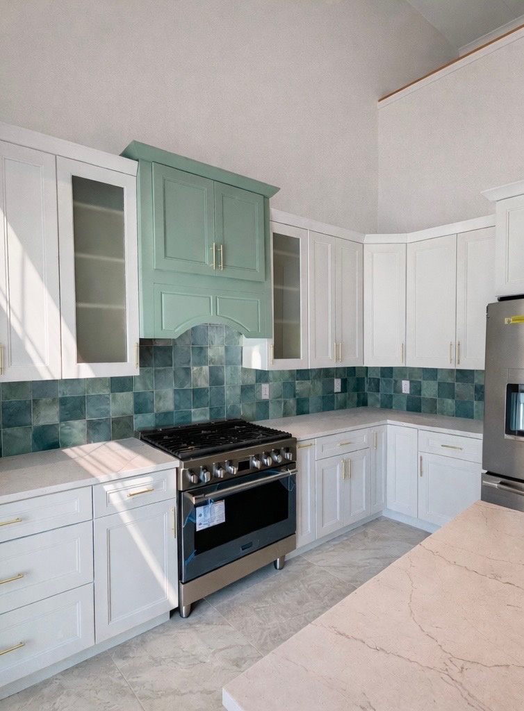 Custom green range hood with hand-glazed tile backsplash
