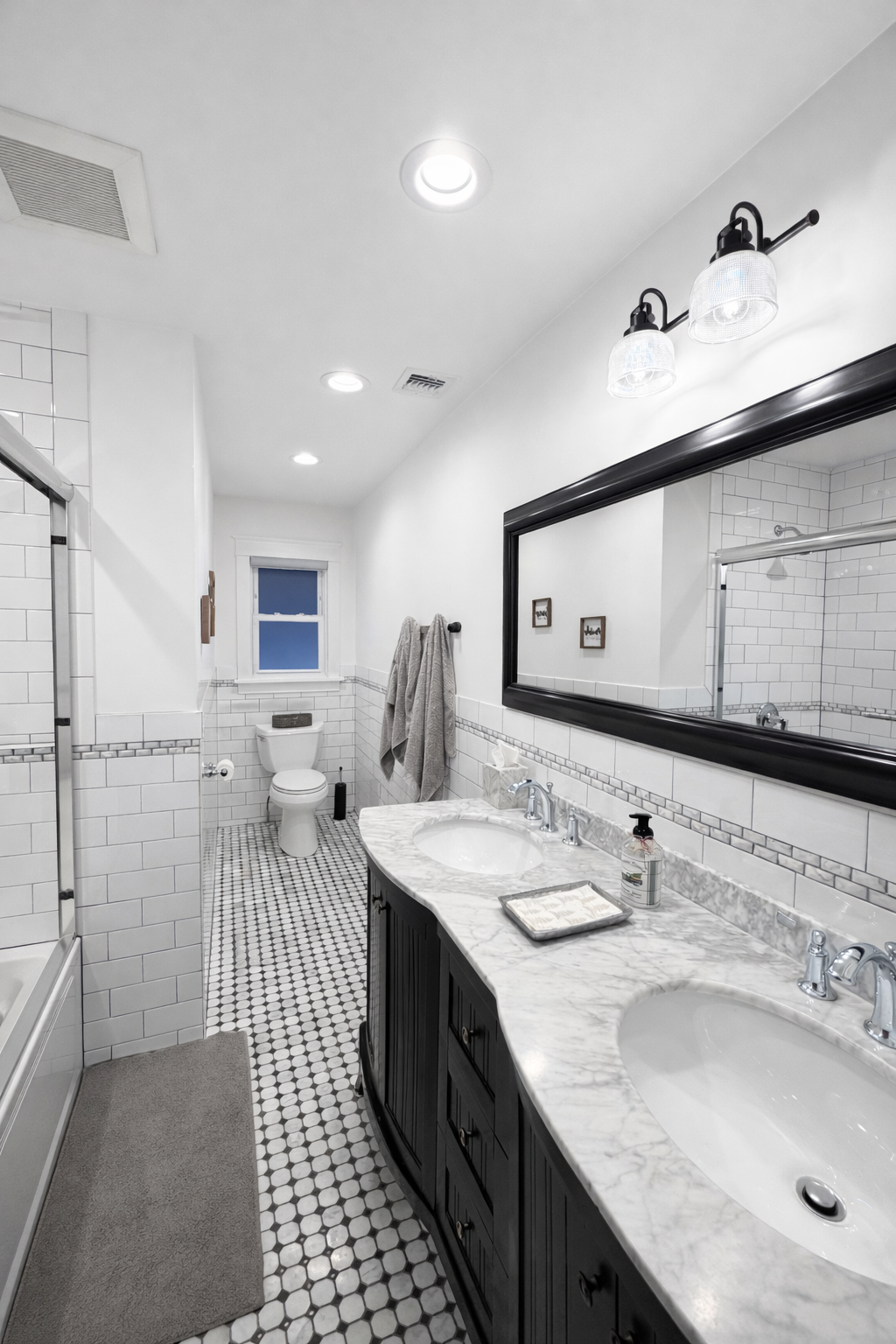 Classic bathroom remodel with white subway tile, penny-round floor, and double marble vanity
